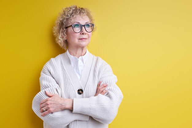 W wieku piękna siwowłosa kobieta mająca poważną twarz myślącą o pytaniu, bardzo zdezorientowany pomysł, nosząca okulary, na białym tle o