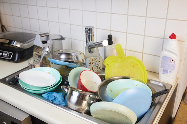 W zlewie jest dużo brudnych naczyń Brudne naczynia i nieumyte sprzęty kuchenne zapełniły zlewozmywak
