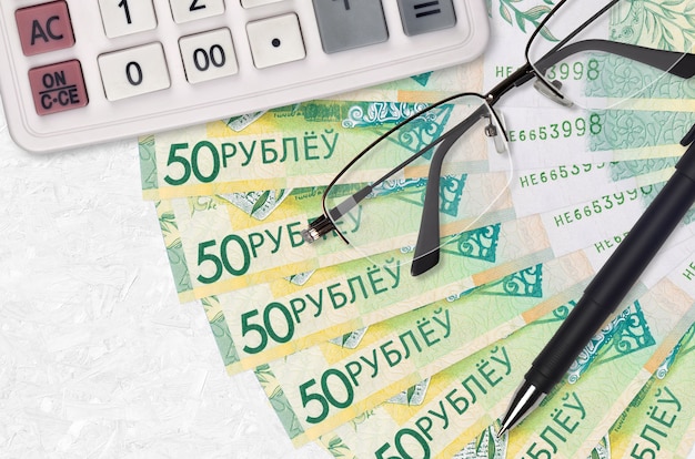 Wachlarz i kalkulator na rachunki za 50 rubli białoruskich, okulary i długopis. Kredyt biznesowy lub koncepcja sezonu płatności podatku. Planowanie finansowe