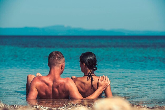 Zdjęcie wakacje i wakacje w podróży miłosne relacje pary cieszą się letnim dniem razem rodzina i walentynki seksowna kobieta i mężczyzna pływają w wodzie morskiej zakochana para relaksuje się na plaży