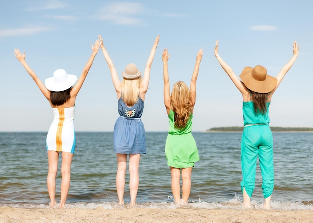 wakacje letnie i koncepcja wakacji - dziewczyny z rękami w górze na plaży