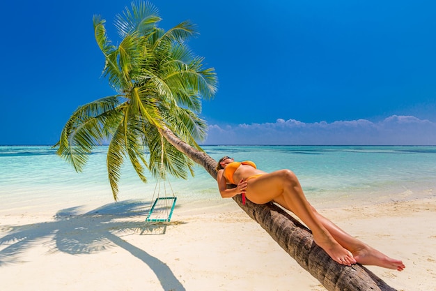 Wakacje młoda seksowna kobieta w pomarańczowym kostiumie kąpielowym bikini leżąc na palmie Beztroska wolność