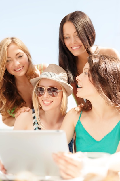 wakacje, wakacje, internet i koncepcja technologii - uśmiechnięte dziewczyny patrzące na komputer typu tablet w kawiarni