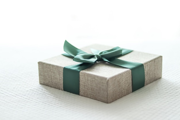 Wakacyjny prezent i luksusowe zakupy online owinięte pudełkiem lnianym z zieloną wstążką na łóżku w eleganckim wiejskim stylu sypialni