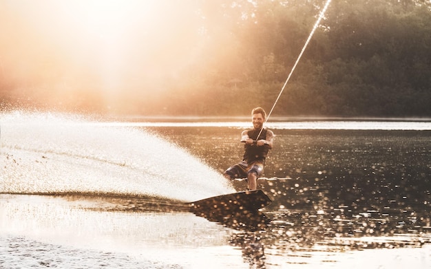 Wakeboarding, Wakeboarder ślizga Się Po Wodzie Z Wakeboardem I Tworzy Rozbryzgi, Złote Godziny Mgły