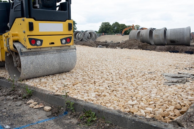 Walec zagęszczający kamień podczas budowy nowej drogi w przygotowaniu do asfaltu, na terenie osiedla mieszkaniowego