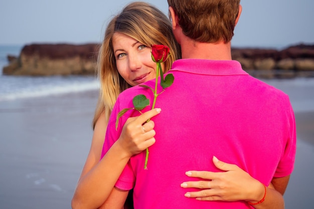 Zdjęcie walentynki 14 lutego mężczyzna daje kobiecie różę stojąc na plaży nad morzem letni poranek