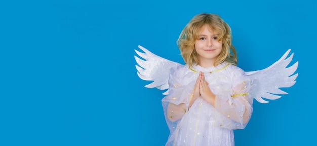 Zdjęcie walentynki blondynka słodkie dziecko z anielskimi skrzydłami z modlitewnymi rękami nadzieja i modlić się koncepcja na niebiesko