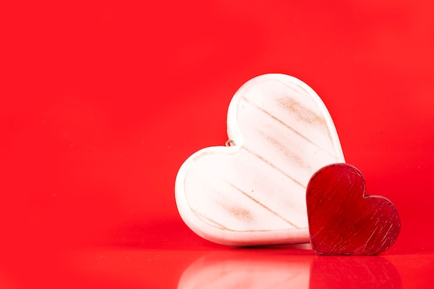 Walentynki dwa drewniane serca malowane na czerwonym tle w rogu