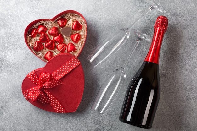 Walentynki kartkę z życzeniami z kieliszkami do szampana i cukierków serca na tle kamienia.