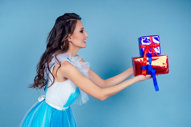 Walentynki kobieta w sukience trzymająca pudełko z prezentami na niebieskim tle w studio.miła dziewczyna otrzymała prezent zaskoczona i zdumiona.Międzynarodowy Dzień Kobiet i koncepcja dnia matki