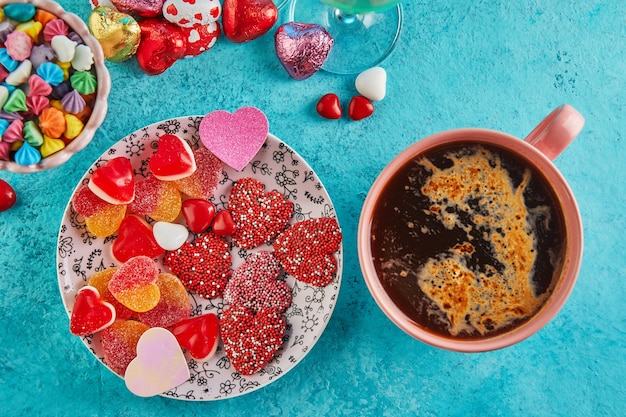Zdjęcie walentynki lub romantyczna kolacja z cukierkowymi serduszkami, filiżanką gorącej kawy i eleganckim nakryciem stołu