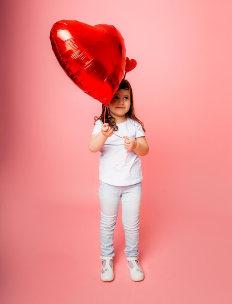 Walentynki, Mała Dziewczynka Trzyma Duży Balon W Kształcie Serca Na Różowym Tle.