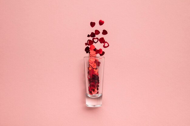 Walentynki strzały kieliszek z konfetti serca na pastelowym różowym tle