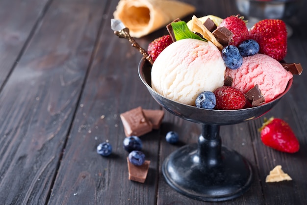 wanilia i truskawka o smaku mrożonego deseru lody w metalowej misce z jagodami na drewnianym