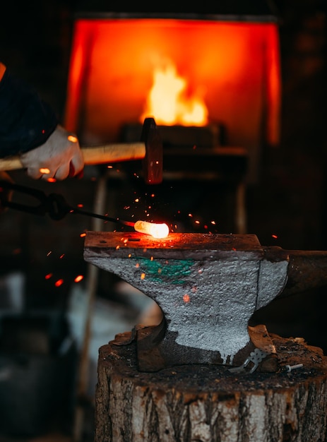 Warsztaty kowalskie. Kowal pracuje na kowadle rozgrzanym kęsem metalu.