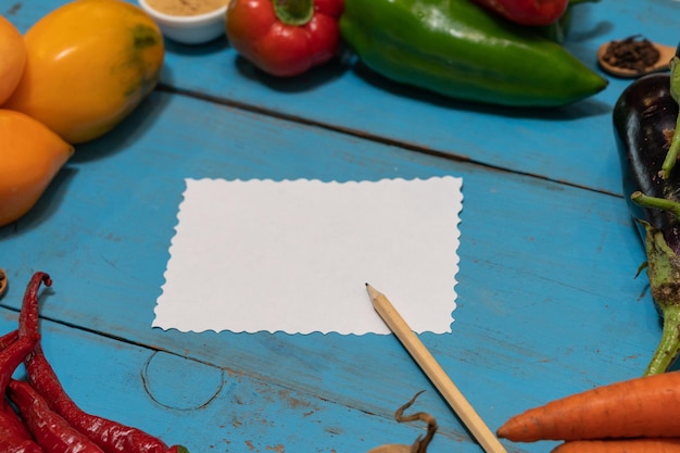 Warzywa są ułożone wokół kartki papieru i ołówka Puste miejsce na tekst