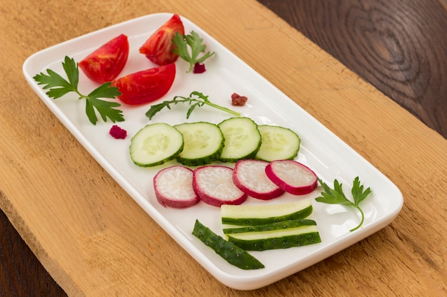 Warzywa w talerzu ceramicznym na nieokrzesanej desce