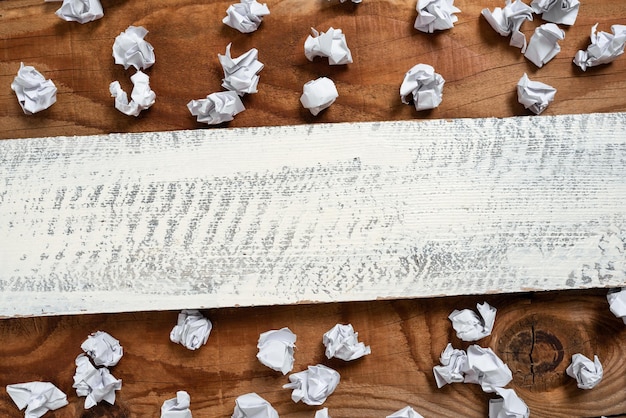 Ważne informacje napisane na kawałku drewna z papierem owija się na podłodze Kluczowe ogłoszenia na drewnianym panelu z pogniecionymi notatkami na całym