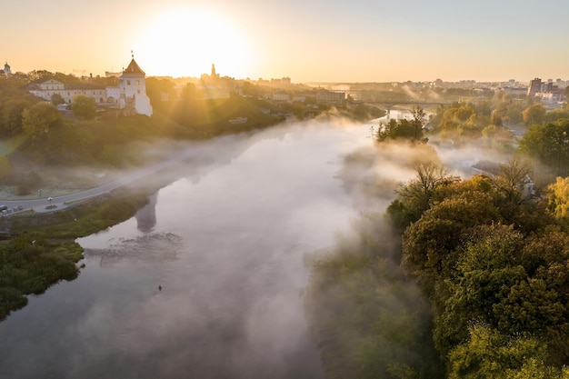 Wcześniej mglisty poranek i panoramiczny widok z lotu ptaka na średniowieczny zamek i promenadę z widokiem na stare miasto i zabytkowe budynki w pobliżu szerokiej rzeki