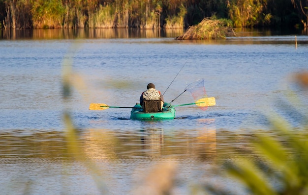 Wczesnym rankiem rybak siedzi w łódce na środku jeziora i łowi ryby