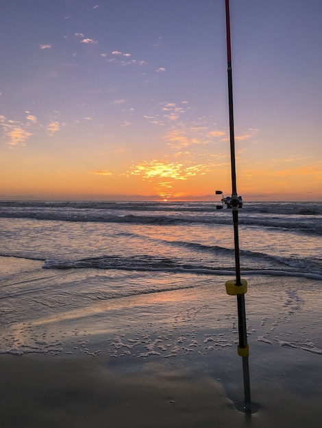 Wędka na plaży o zachodzie słońca, surfing, obsada