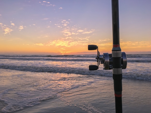 Wędka na plaży o zachodzie słońca, surfing, obsada