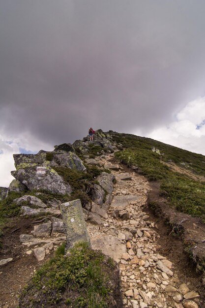 Wędrowcy z kijkami trekkingowymi na scenicznej fotografii górskiego klifu