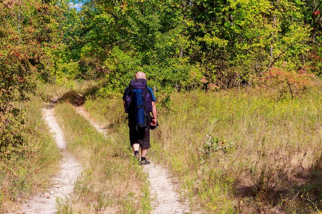 Zdjęcie wędrówka z plecakiem po polnej drodze w zielonym lesie widok z tyłu