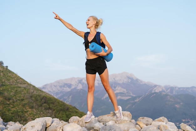 Wędrówki latem Emocjonalna młoda kobieta wskazuje ręką na bok Widok na pasmo górskie