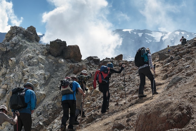 Wędrująca grupa ludzi na szlaku turystycznym wspina się po stromym zboczu do krateru aktywnego wulkanu