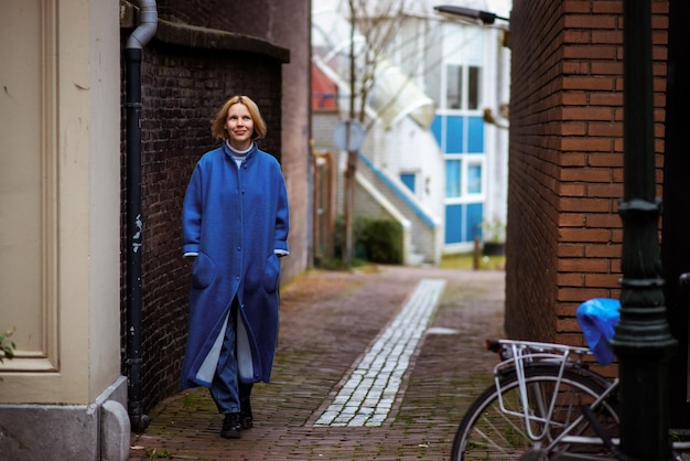 Weekend w Holandii kobieta w niebieskim płaszczu idzie wzdłuż drogi Odpoczynek w podróży po Europie