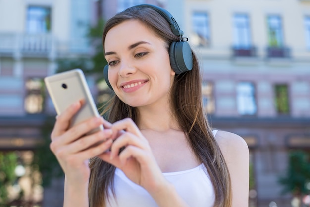 Weekendowe wakacje relaks reszta koncepcji dźwięku studenta. Zbliżenie portret wesoły marzycielski zadowolony całkiem marzycielski pokojowy ona jej pani trzymając telefon w ręce, wybierając pobieranie piosenki