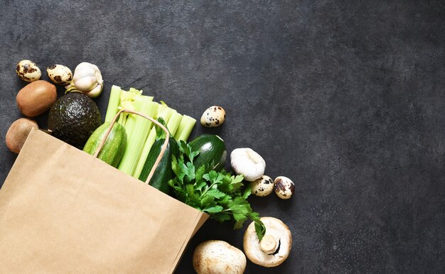 Wegańska koncepcja zakupów lub dostawy żywności, świeże zielone produkty w papierowej torbie.