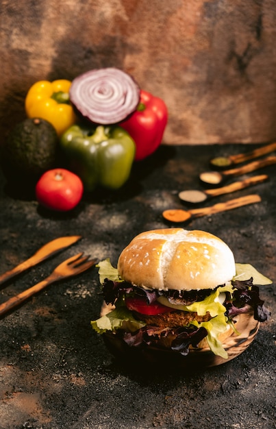 Wegański burger Seitan na drewnianej powierzchni z warzywami. Zdrowe wegańskie jedzenie