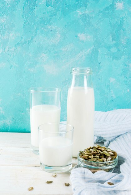 Wegańskie jedzenie alternatywne, nasiona dyni niemlecznego mleka na jasnoniebieskim tle, miejsce
