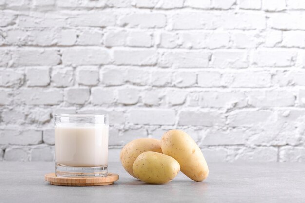 Wegańskie mleko ziemniaczane i ziemniaki na szarym tle kamiennego stołu alternatywny preparat mlekozastępczy na bazie roślin