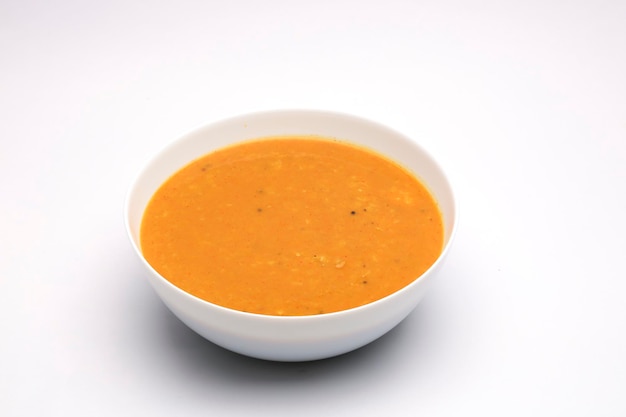 Wege curry lub dal curry, żółte curry, główne danie Indian i dobre połączenie do chappati i dań ułożonych w białej misce na białym teksturowanym tle.