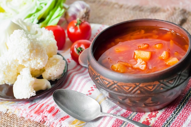 Wegetariańska zupa pomidorowa z kapustą i kalafiorem w ceramicznej misce rustykalnej