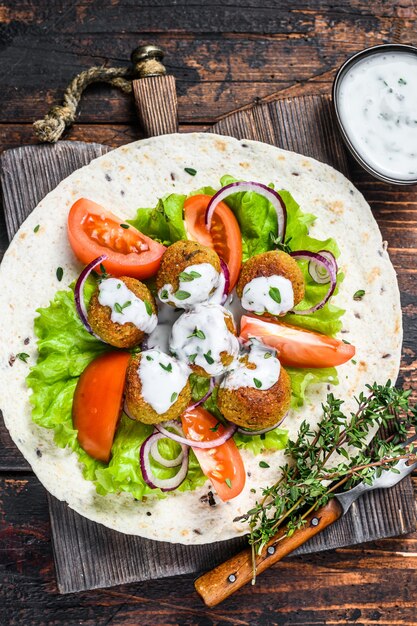 Wegetariański falafel z warzywami i sosem tzatziki na tortilli.