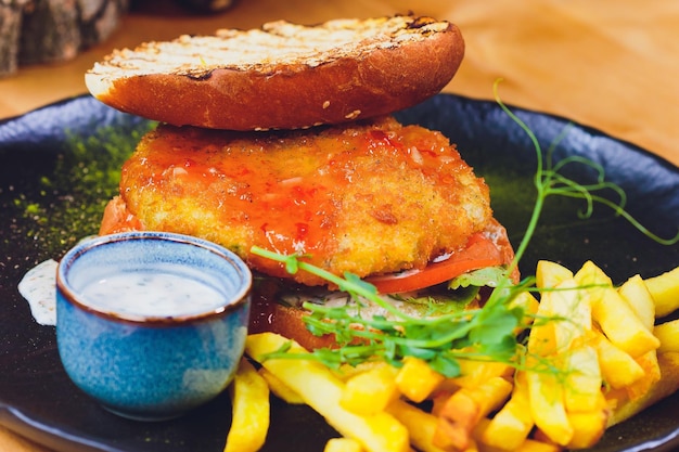 Zdjęcie wegetariański hamburger z soczewicą w bułeczce pełnoziarnistej z sałatką, pomidorem i ogórkiem wraz z frytkami selective focus focus na przedniej stronie kanapki
