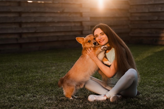 Welsh Corgi Pembroke Pies Całuje Swoją Dziewczynę Właściciela Na Trawie Styl życia Z Domowym Zabawnym Zwierzakiem Młoda Kobieta Przytula Się Uroczo Corgi Pies I Uśmiech Na Zewnątrz