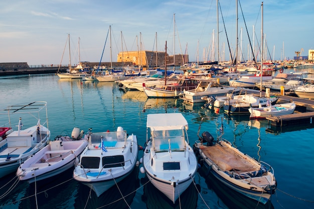 Wenecki zamek fort w Heraklionie i zacumowane łodzie rybackie, Kreta, Grecja na zachód słońca