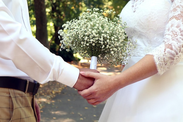 Wesele to kłopotliwa sprawa delikatny bukiet w rękach Pary Młodej na tle zbliżenia parkowej alei