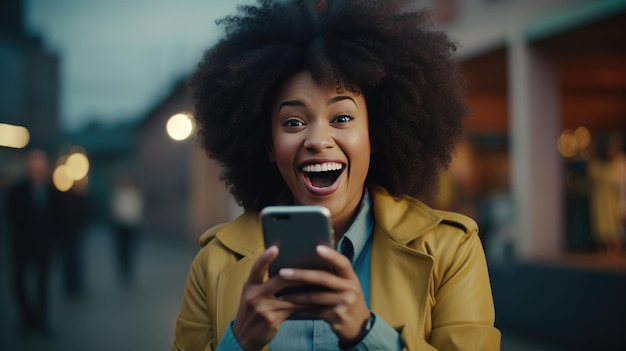 Wesoła afroamerykańska kobieta świętuje zwycięstwo ze smartfonem na kanapie Wesoła dama zaręczona dowcipem