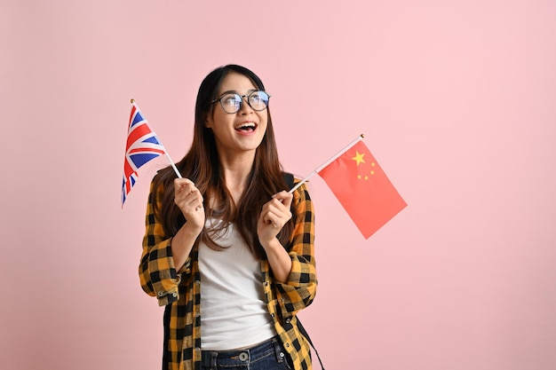 Wesoła azjatycka studentka college'u trzymająca flagi Anglii i Chin