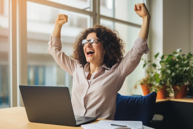 Wesoła bizneswoman freelancer przedsiębiorca uśmiecha się i cieszy się zwycięstwem, siedząc przy biurku