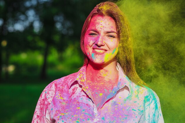 Wesoła brunetka kaukaska dziewczyna bawiąca się kolorową suchą farbą na festiwalu Holi