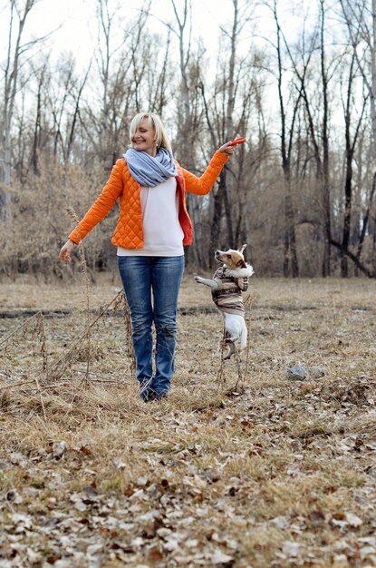 Wesoła dziewczyna bawiąca się z psem w parku Jack Russell jest w skoku