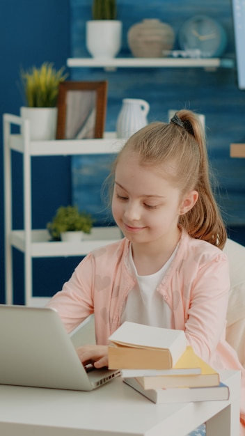 Wesoła dziewczyna patrząca na ekran laptopa na zdalne zajęcia online